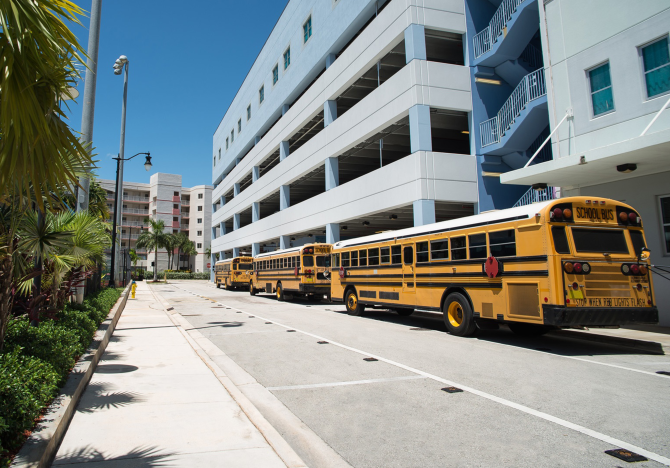 school-buses-parked-along-sidewalk-outside-buildings