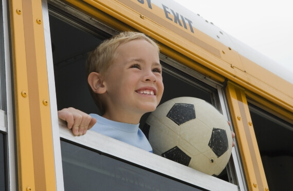 smiling-boy-school-bus-window-soccer-ball